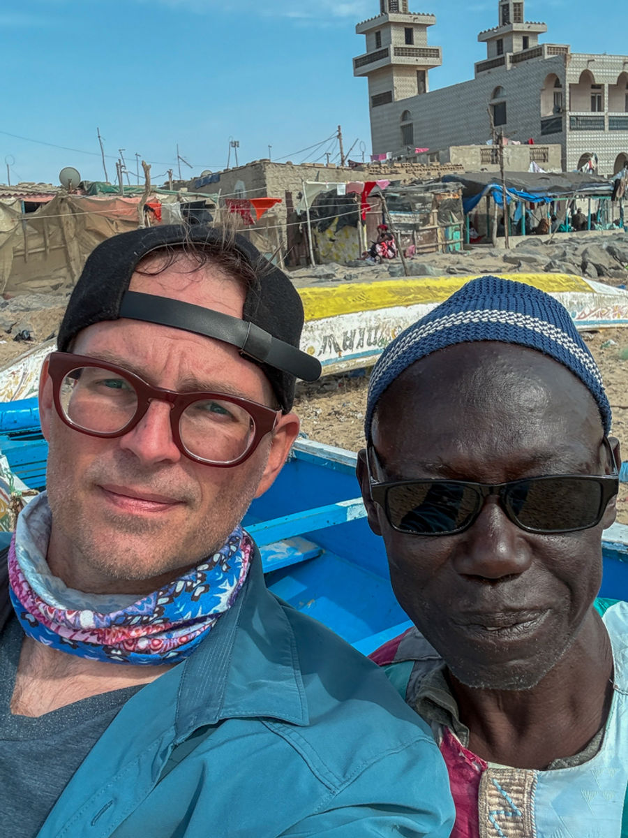 Cheikh and I posing for a selfie beside a fishing boat