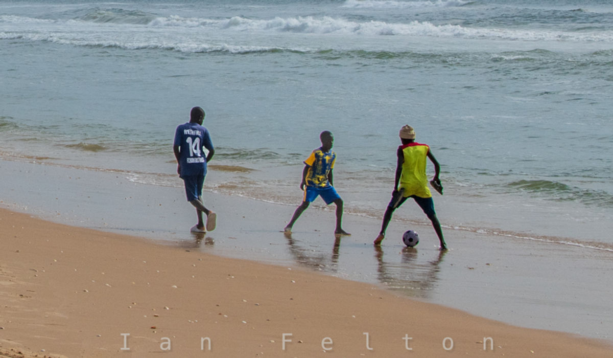 Kids playing soccer nearby while the adults worked