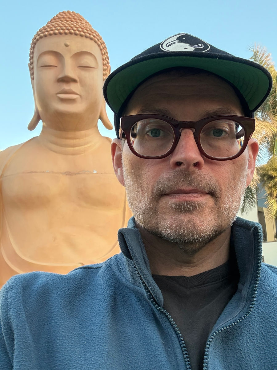 The traveler in front of the Buddha statue outside his room on the hotel grounds